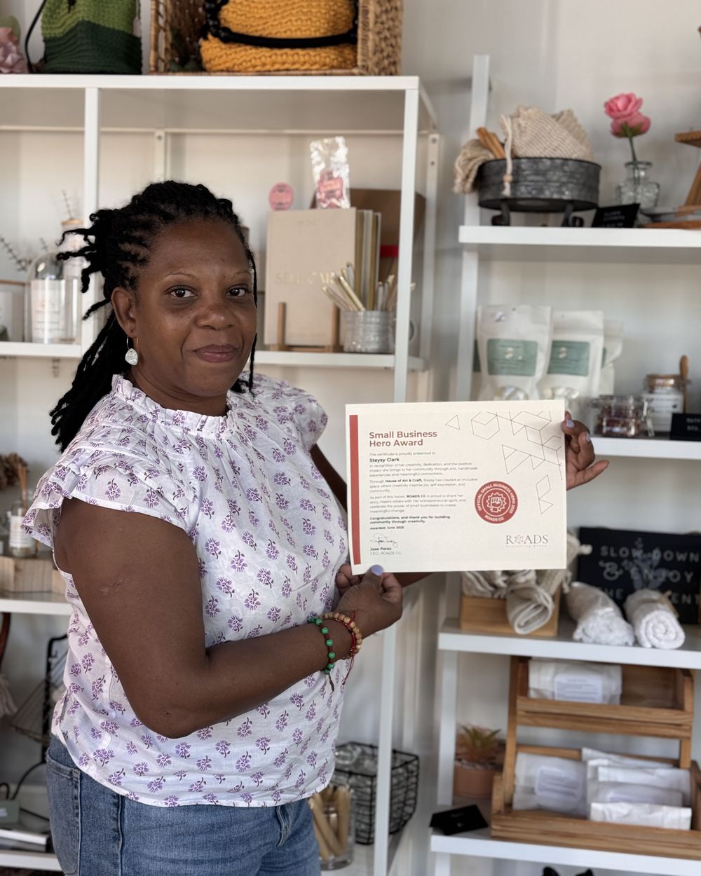 Steysy Clark holding her Small Business Hero Award certificate in House of Art & Craft